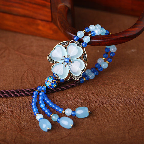blue long necklace, with Oriental style decorations, and blue crystals organized into shape of a lucky clover leaf.